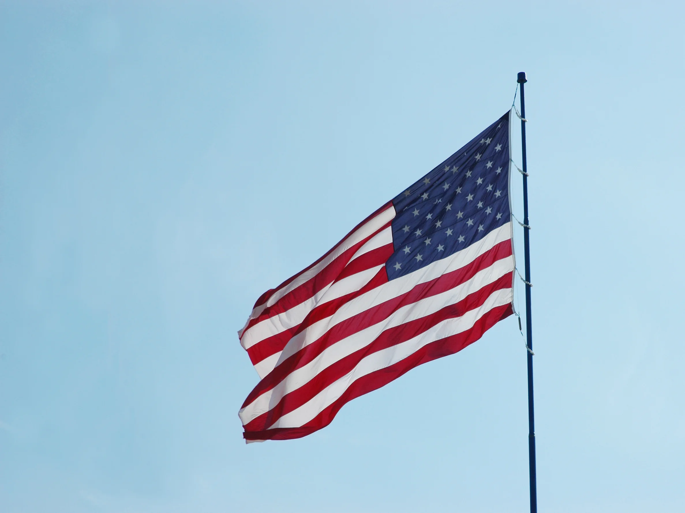 American flag waving against the sky, representing cancellation of removal cases in U.S. immigration court