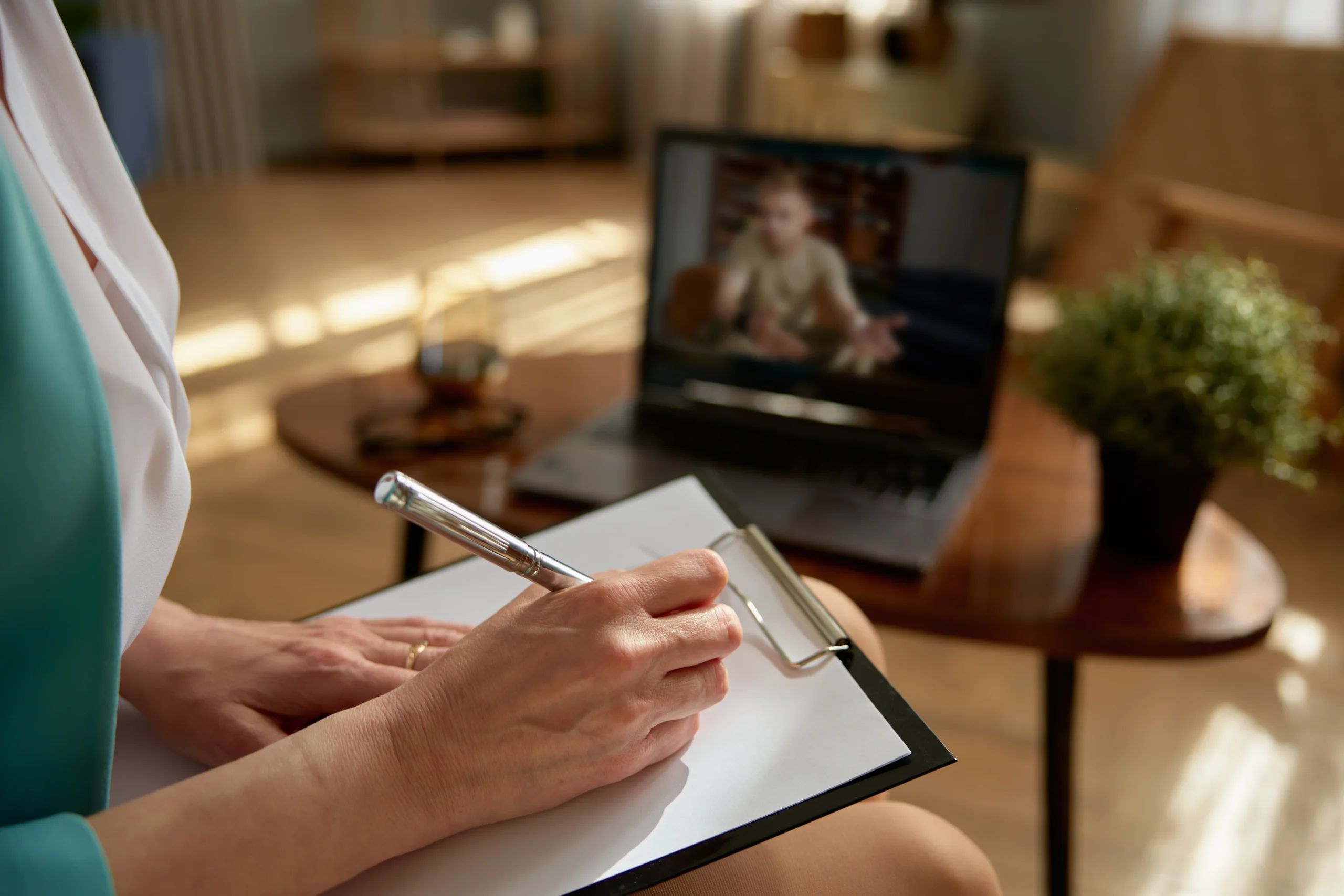 Clinician taking notes on a clipboard during a secure video psychiatric assessment