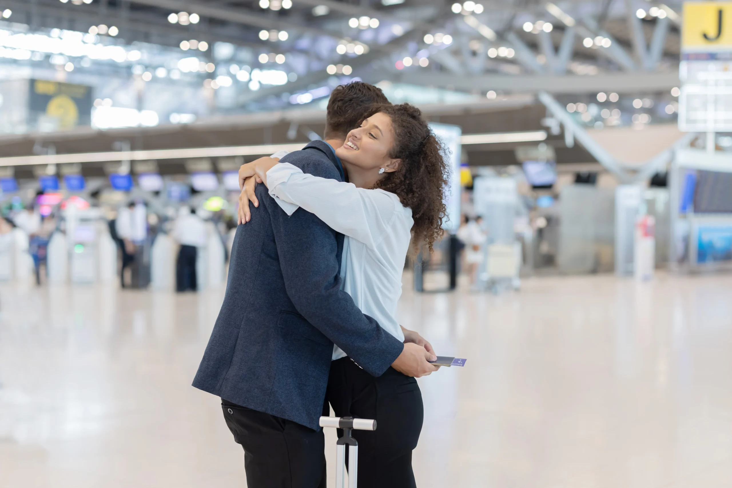 Couple embracing at an airport before a consular interview abroad, facing possible separation