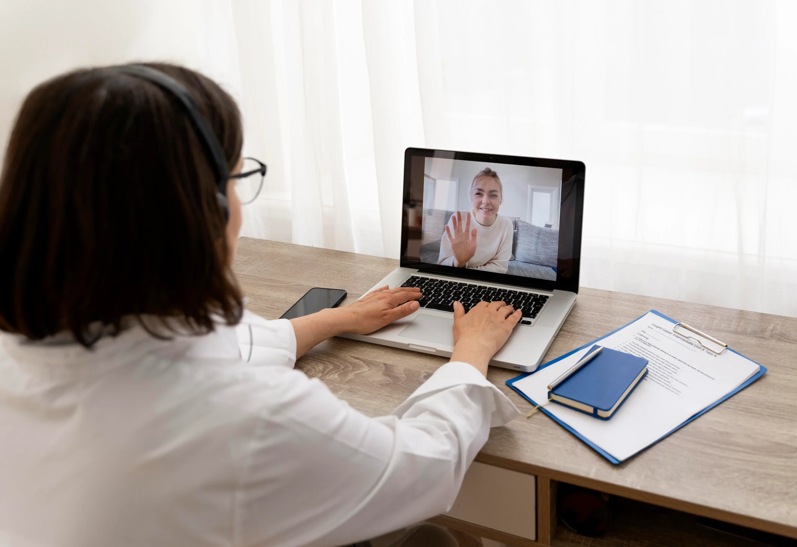 Provider with a headset greeting a client over laptop video during an online psychiatric evaluation