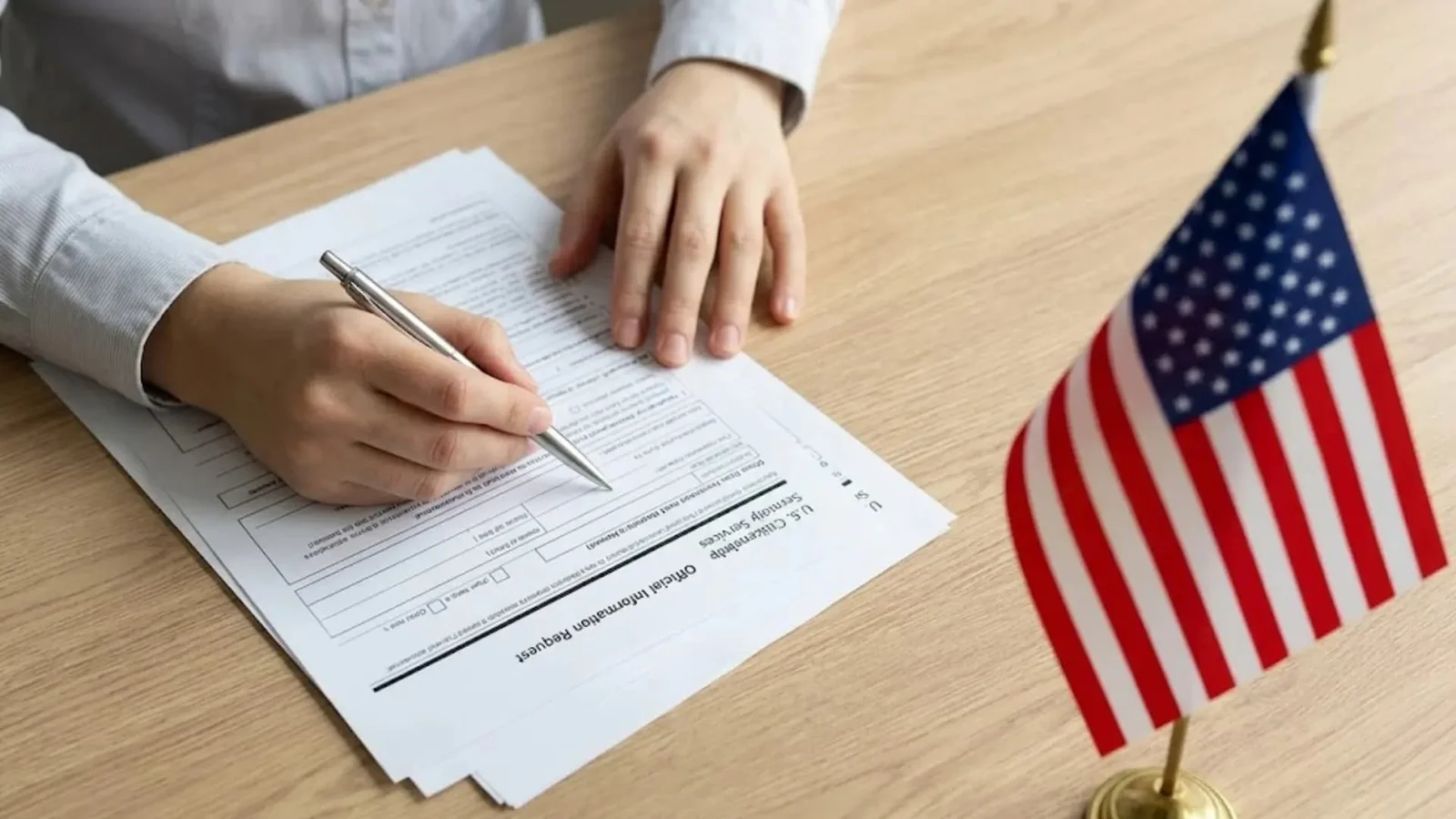 Person filling out a USCIS form beside an American flag, representing a U visa petition based on a qualifying crime