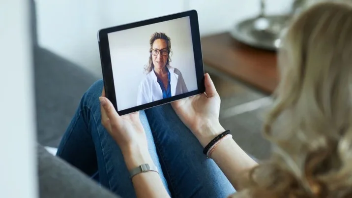 Woman holding a tablet during a private, secure telehealth session with a provider