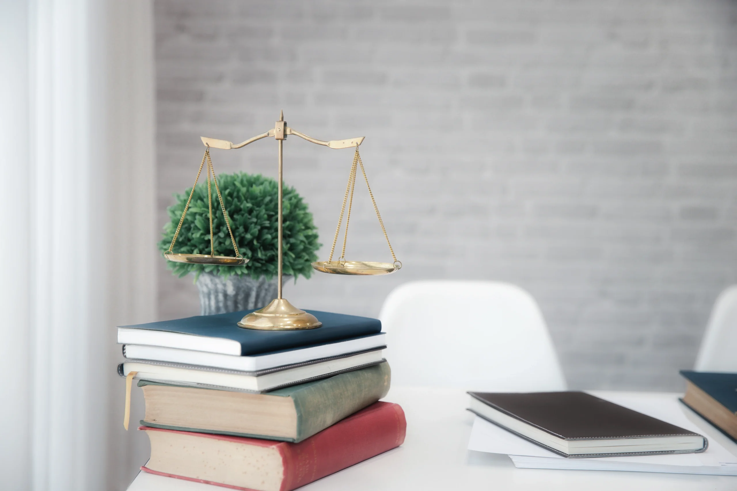 Gold scales of justice on a stack of law books, representing the T visa requirements a clinical report can support