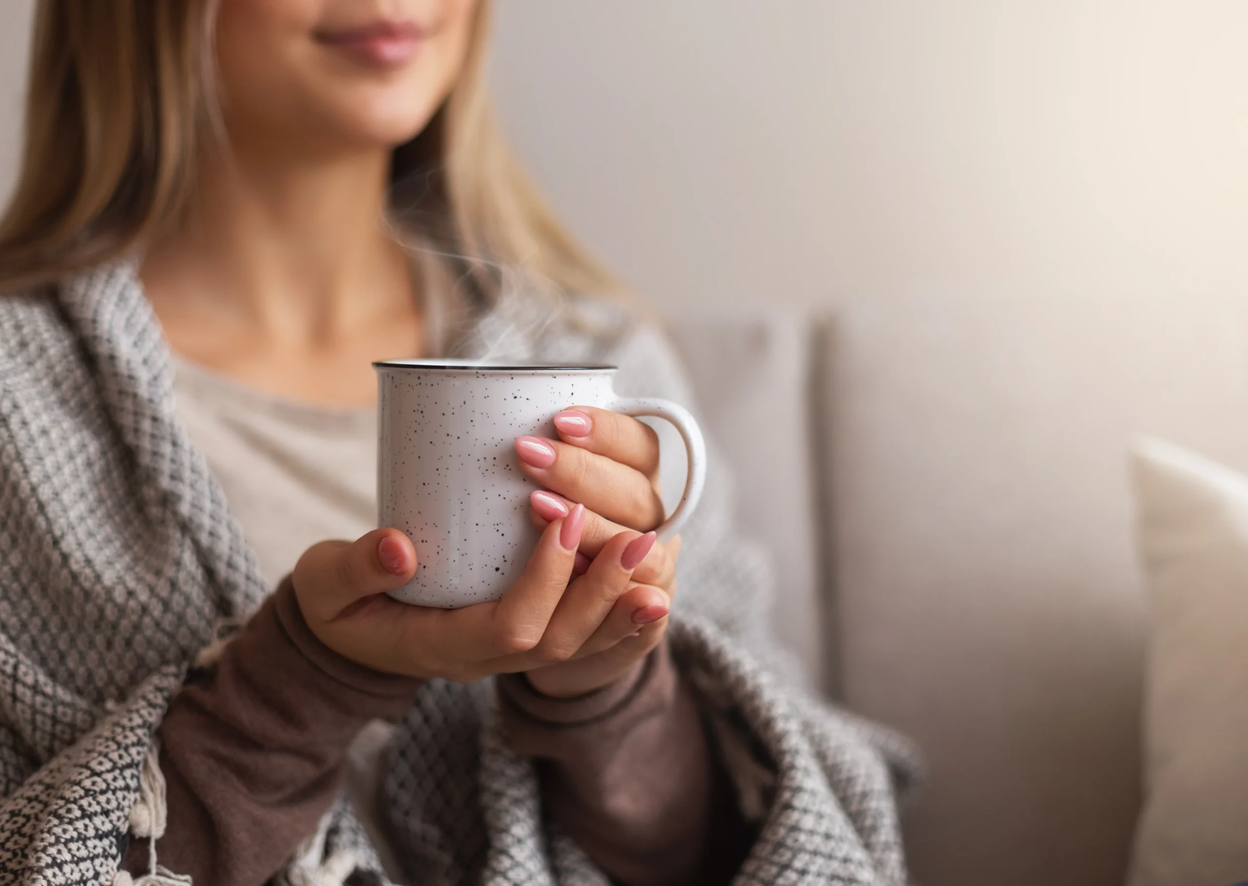Woman wrapped in a soft blanket holding a warm cup of tea, reflecting a calm, trauma-informed space for crime survivors
