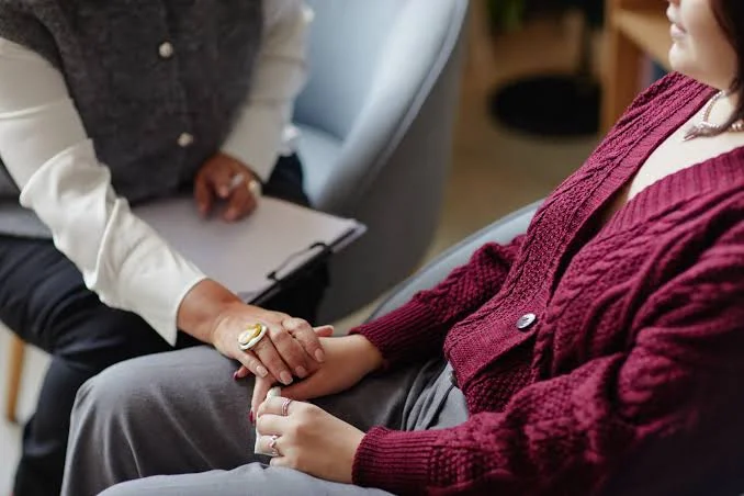 Clinician holding a client's hands in support during a trauma-informed T visa evaluation