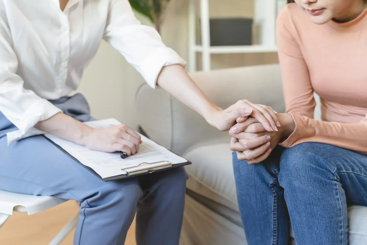 Clinician gently holding a client's hands, showing confidential, trauma-informed care