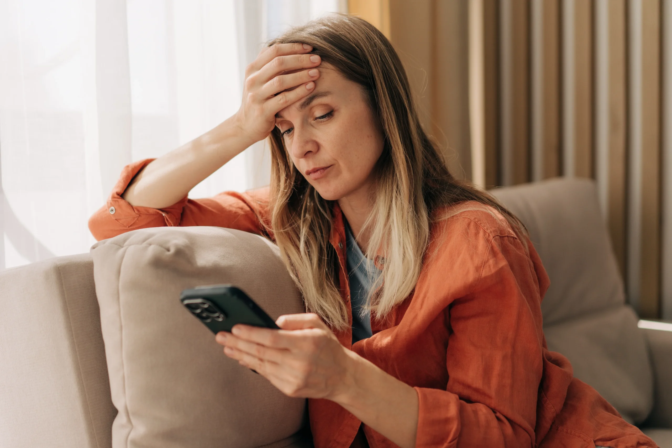 Anxious woman reading her phone, reflecting threats and control that count as extreme cruelty under VAWA