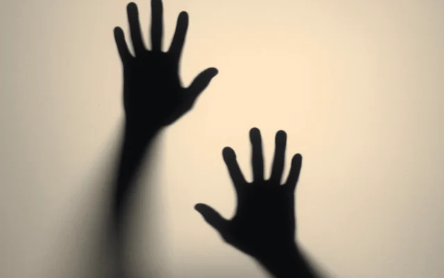 Shadows of raised hands on a wall, representing domestic abuse addressed in a VAWA psychological evaluation