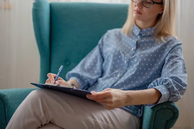 Psychologist writing clinical notes on a clipboard during a VAWA self-petition evaluation