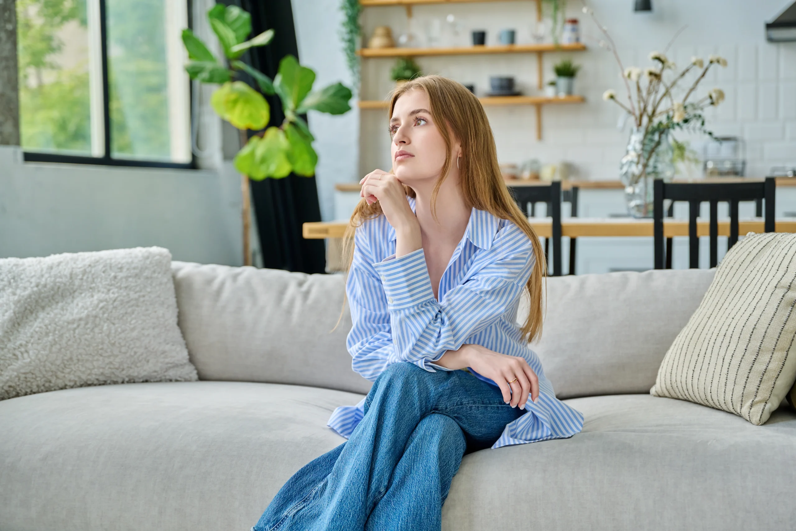 Person sitting alone at home in thought, considering a VAWA self-petition
