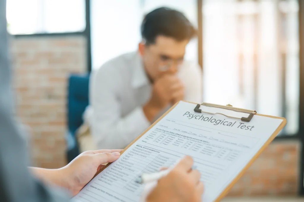 Clinician completing a forensic psychological evaluation form while patient speaks during a USCIS immigration assessment